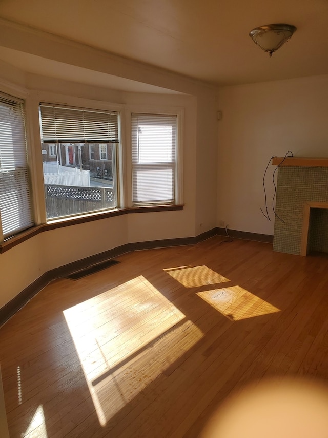 spare room featuring a tiled fireplace and light hardwood / wood-style flooring