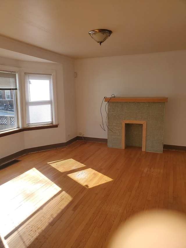 unfurnished living room with a tile fireplace and light hardwood / wood-style floors