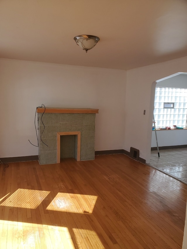 unfurnished living room with a tile fireplace and hardwood / wood-style floors