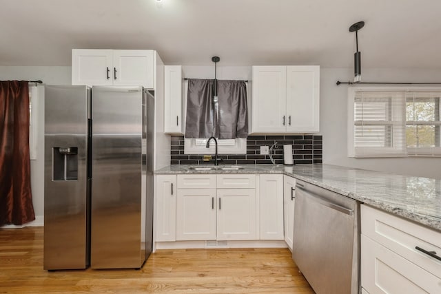 kitchen featuring appliances with stainless steel finishes, light hardwood / wood-style floors, hanging light fixtures, and sink