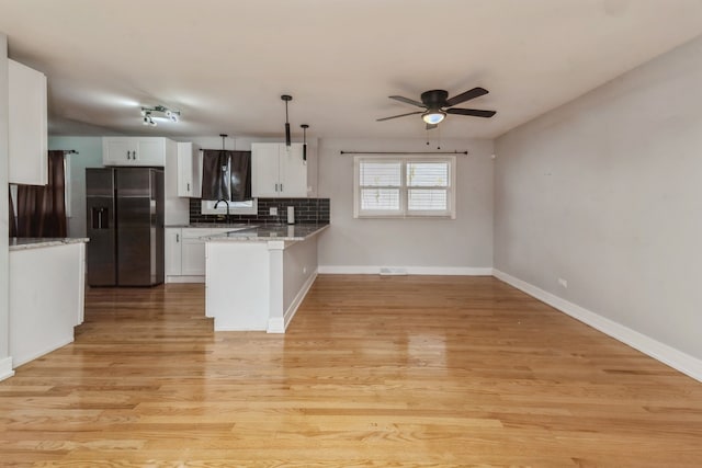 kitchen featuring hanging light fixtures, stainless steel refrigerator with ice dispenser, kitchen peninsula, white cabinets, and light wood-type flooring