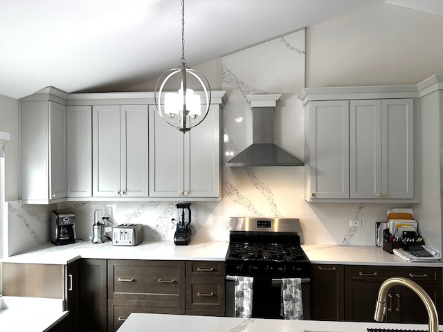 kitchen with pendant lighting, lofted ceiling, an inviting chandelier, wall chimney exhaust hood, and stainless steel gas stove