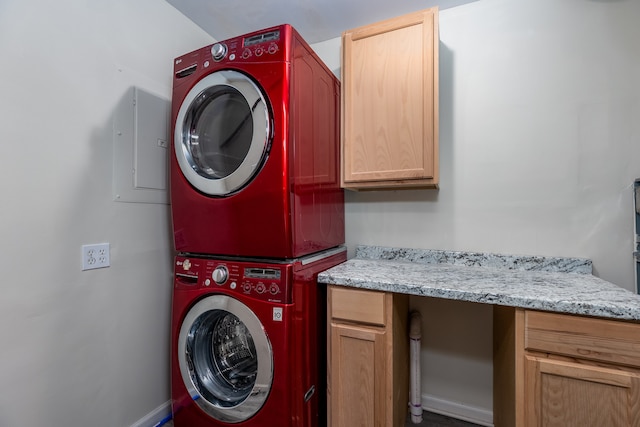 washroom with cabinets and stacked washer and clothes dryer