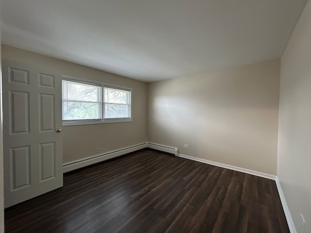 unfurnished room featuring dark hardwood / wood-style flooring and a baseboard heating unit