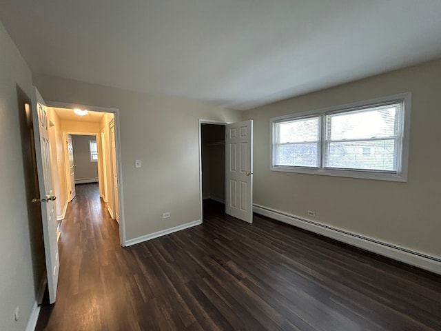 unfurnished bedroom with dark hardwood / wood-style floors, a baseboard radiator, and a closet