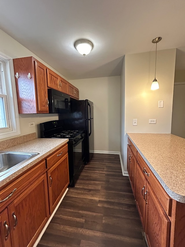 kitchen featuring black appliances, sink, hanging light fixtures, and dark wood-type flooring