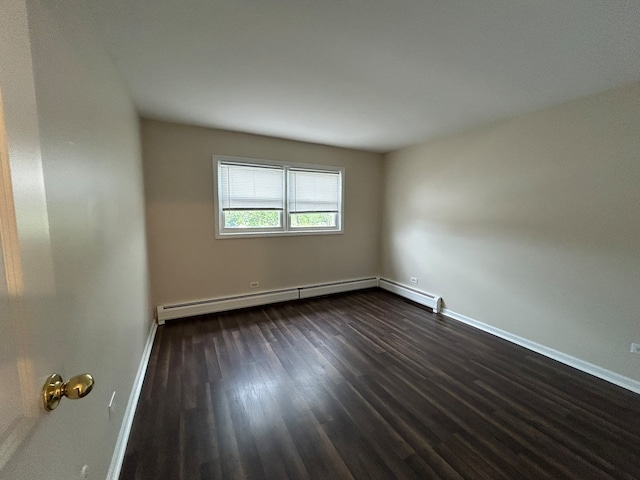 spare room with dark hardwood / wood-style flooring and a baseboard radiator