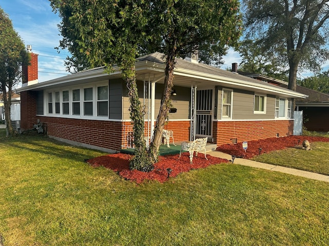 view of front of home with brick siding, a chimney, and a front lawn