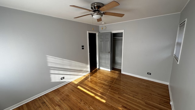 unfurnished bedroom with ceiling fan, dark wood-type flooring, and a closet