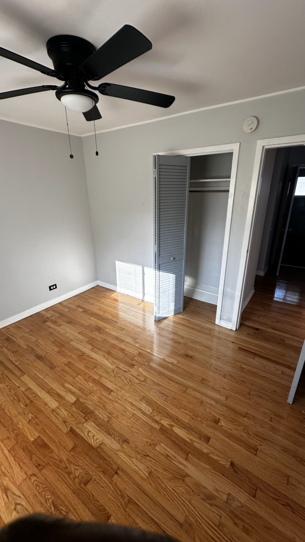 unfurnished bedroom with ceiling fan and wood-type flooring