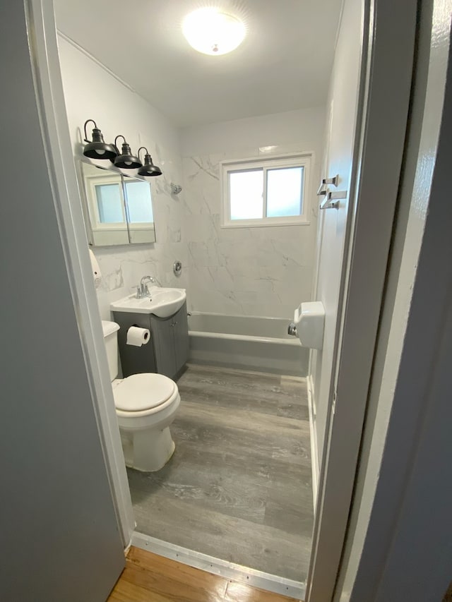 full bathroom featuring vanity, hardwood / wood-style flooring, toilet, and tiled shower / bath