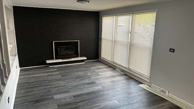 unfurnished room with dark hardwood / wood-style floors and brick wall