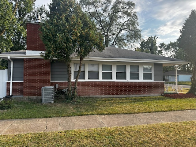 view of home's exterior with central air condition unit, brick siding, and a lawn