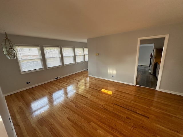 spare room with hardwood / wood-style flooring and a notable chandelier