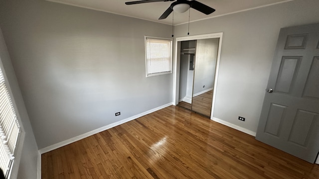 unfurnished bedroom featuring hardwood / wood-style flooring, ceiling fan, crown molding, and a closet