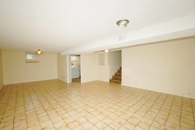 basement featuring washer / dryer, a textured ceiling, and light tile patterned floors