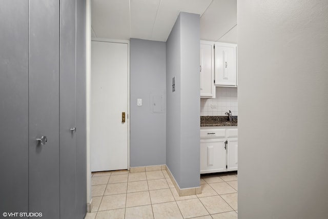 interior space with white cabinets, light tile patterned floors, dark stone counters, and tasteful backsplash