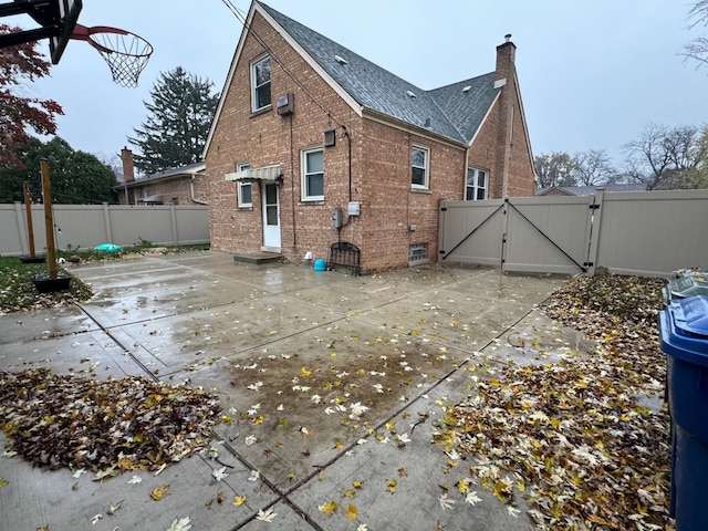 rear view of house with a patio area and basketball hoop