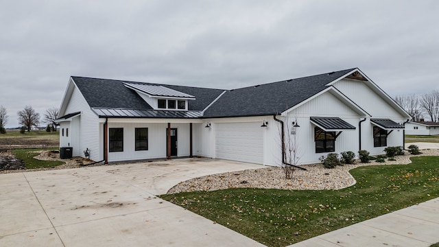 modern farmhouse featuring a front yard, a garage, and central AC unit