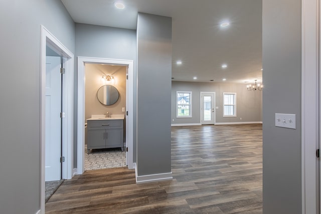 hallway with a chandelier, dark hardwood / wood-style floors, and sink