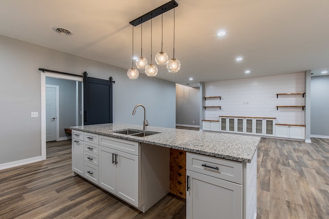 kitchen featuring white cabinets, a barn door, hardwood / wood-style flooring, and sink