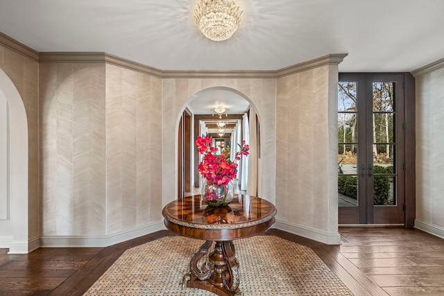 foyer entrance with a notable chandelier, dark hardwood / wood-style flooring, ornamental molding, and french doors