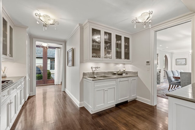 bar with ornamental molding, white cabinetry, sink, and dark wood-type flooring