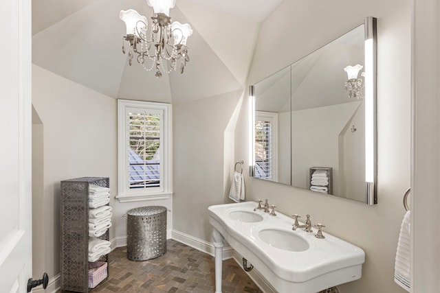 bathroom with double sink, lofted ceiling, and an inviting chandelier