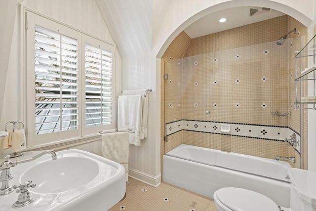 full bathroom with sink, tile patterned floors, bath / shower combo with glass door, vaulted ceiling, and toilet