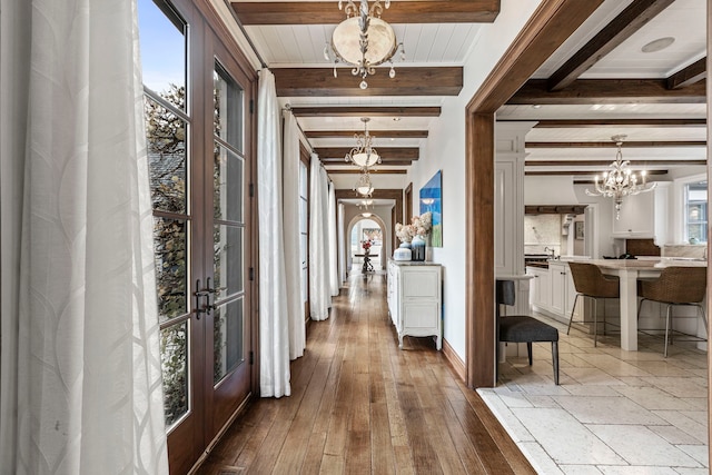 hall with a wealth of natural light, beam ceiling, an inviting chandelier, and french doors