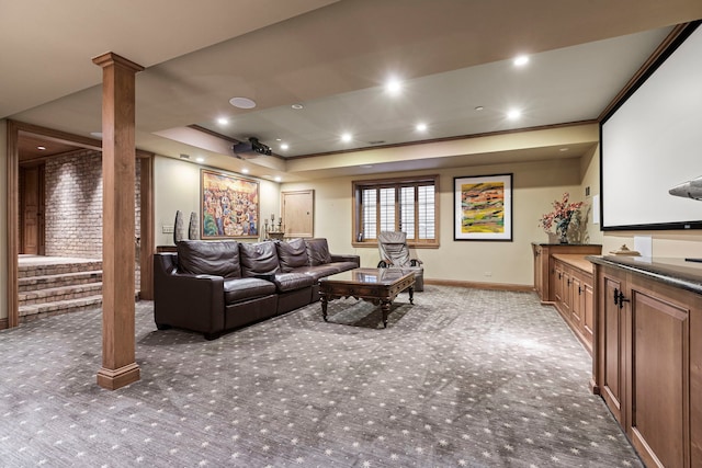 carpeted home theater featuring a raised ceiling and ornamental molding