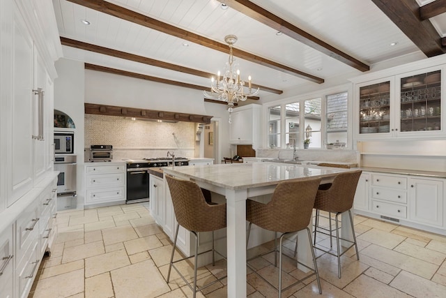 kitchen with white cabinetry, a center island, beamed ceiling, backsplash, and appliances with stainless steel finishes