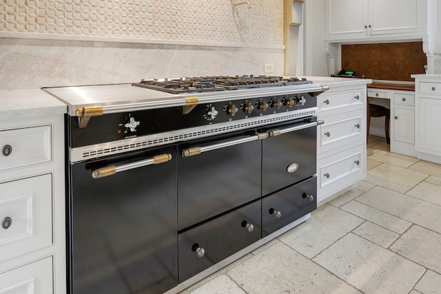 kitchen featuring decorative backsplash, stainless steel stove, and white cabinetry