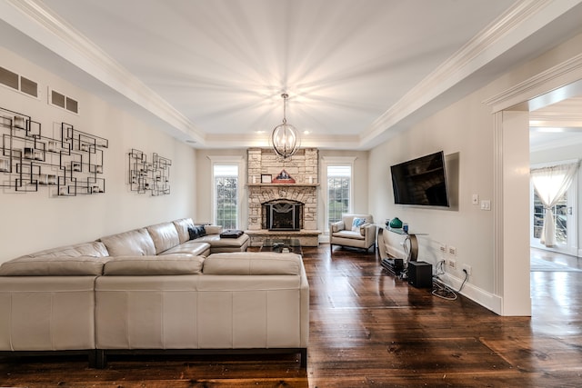 living room featuring crown molding, a fireplace, dark wood-type flooring, and an inviting chandelier