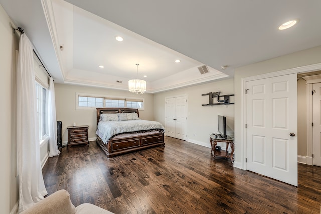 bedroom with a chandelier, dark hardwood / wood-style flooring, and a raised ceiling