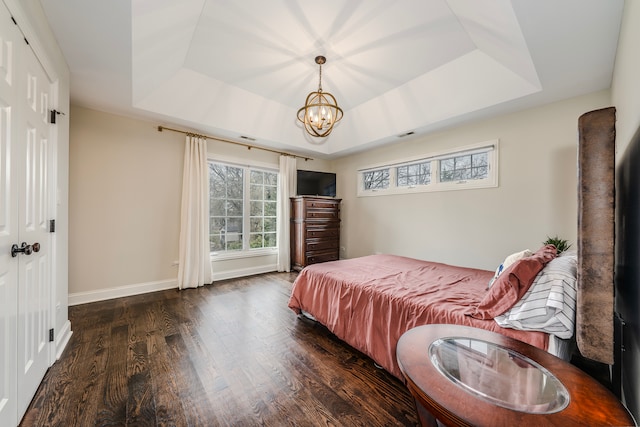 bedroom featuring a raised ceiling, dark hardwood / wood-style flooring, and an inviting chandelier