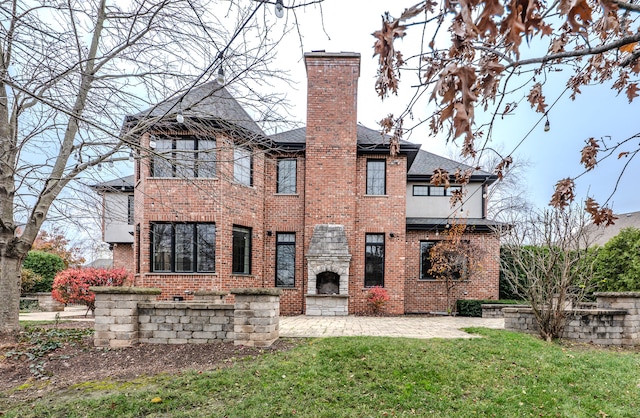 rear view of property featuring a yard, a patio, and a balcony