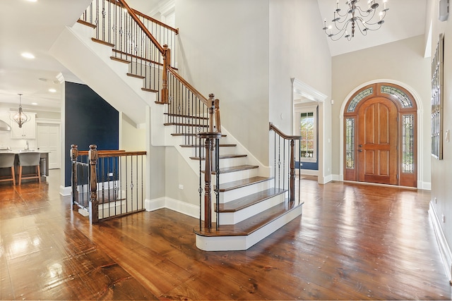 entryway featuring dark hardwood / wood-style floors, a towering ceiling, and an inviting chandelier