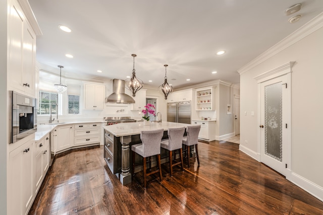 kitchen featuring a breakfast bar, a center island, dark wood-type flooring, wall chimney range hood, and appliances with stainless steel finishes