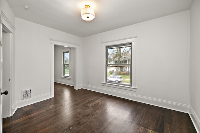 spare room featuring plenty of natural light and dark hardwood / wood-style flooring