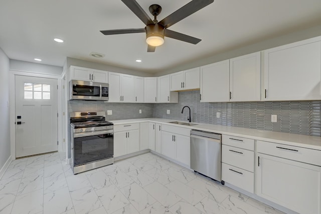 kitchen featuring backsplash, sink, ceiling fan, white cabinetry, and stainless steel appliances