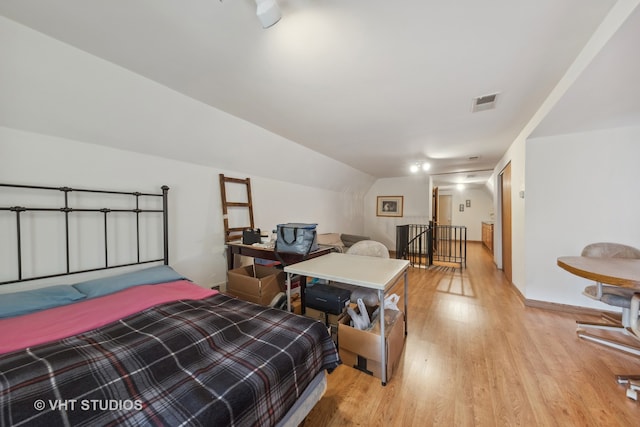 bedroom with light hardwood / wood-style floors and lofted ceiling