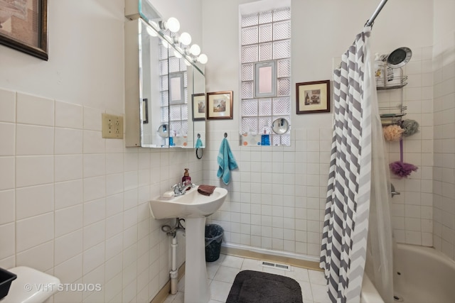 bathroom featuring tile patterned flooring, sink, shower / bath combo with shower curtain, and tile walls