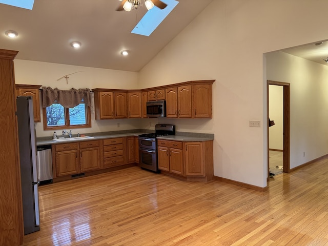 kitchen featuring a skylight, sink, stainless steel appliances, high vaulted ceiling, and light hardwood / wood-style floors