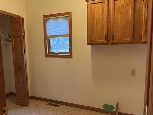 clothes washing area with light tile patterned floors