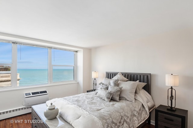 bedroom featuring dark wood finished floors, an AC wall unit, a water view, and a baseboard radiator