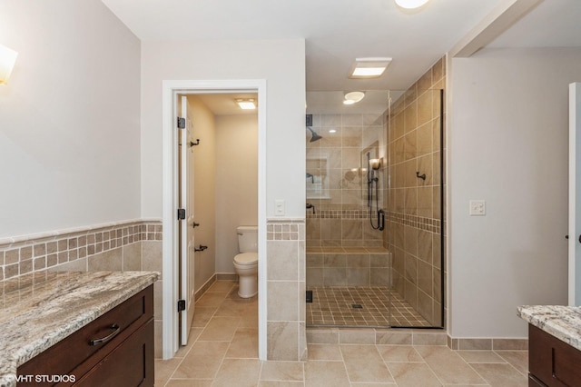 bathroom featuring tile walls, toilet, vanity, and walk in shower