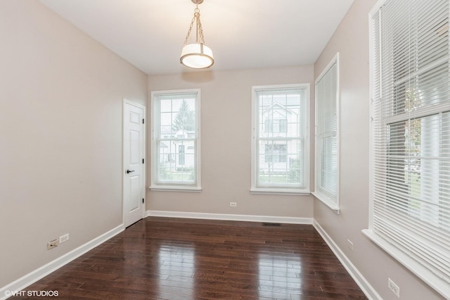 spare room with dark wood-type flooring and a healthy amount of sunlight