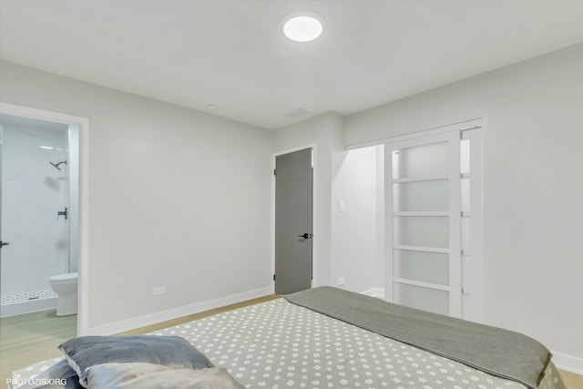 bedroom featuring ensuite bathroom and light wood-type flooring