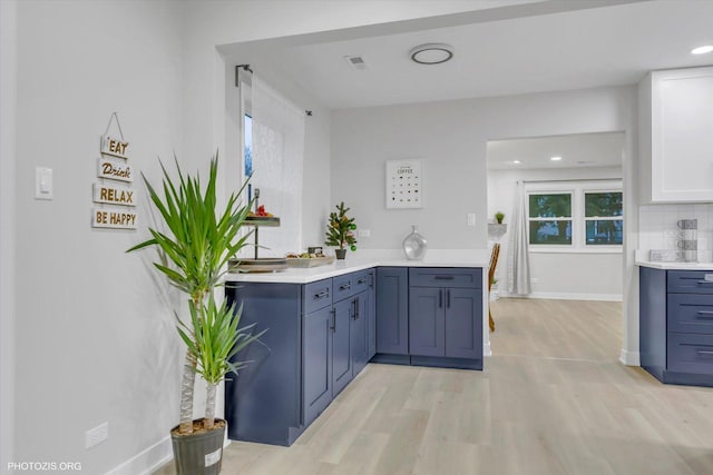 kitchen featuring stainless steel appliances, a barn door, light hardwood / wood-style flooring, decorative backsplash, and white cabinets